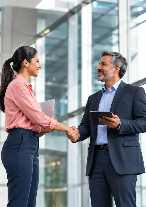 Two PGPSM alumni shaking hands in a modern office corridor